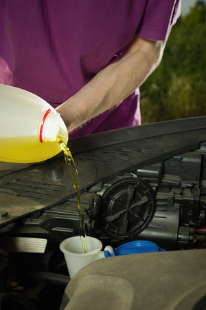 Older driver on longer trip topping up tank with washer fluid