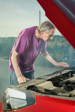 Pensioner checking state of his car with smoking engineの写真素材