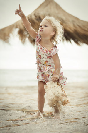 Two and a half year old girl posing on sea beach with giant shellの写真素材
