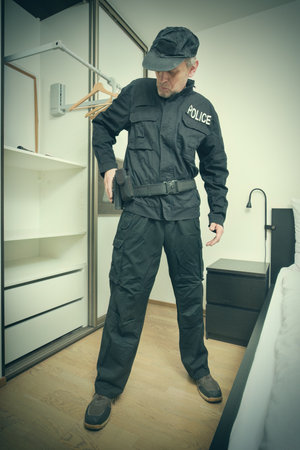 Older slim city police officer dressing up in bedroom for serviceの写真素材
