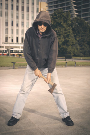 Aggressive older man with ax under the influence of drugs in parkの写真素材