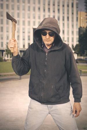 Aggressive older man with ax under the influence of drugs in parkの写真素材