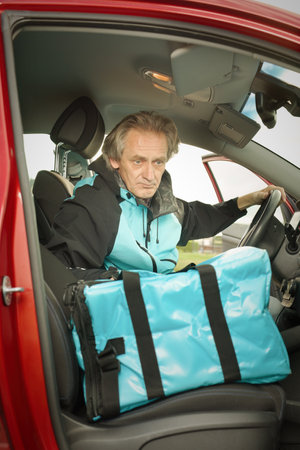 Older man in car delivering food order to it's customerの写真素材