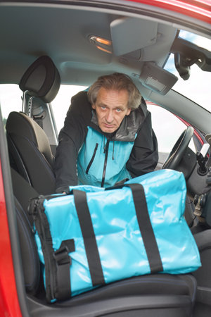 Older man in car delivering food order to it's customerの写真素材