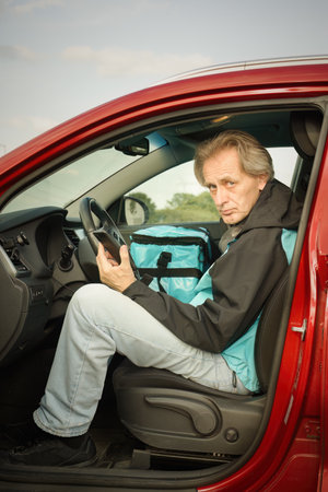 Older man in car delivering food order to it's customerの写真素材