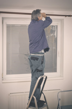 Older man disassembling wall console in empty apartmentの写真素材