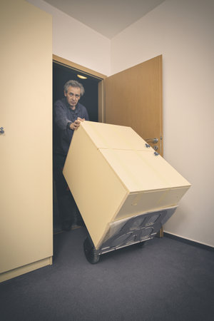 Older man disassembles cabinet in empty apartment ready for paintingの写真素材