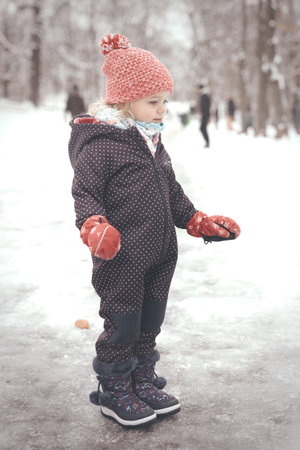 Two years old girl enjoying snow and ice in frozen city parkの写真素材