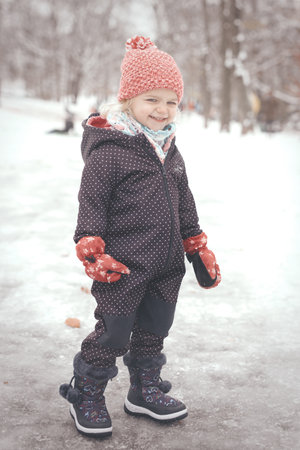 Two years old girl enjoying snow and ice in frozen city parkの写真素材