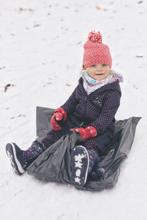 Two years old girl enjoying snow and ice in frozen city parkの写真素材