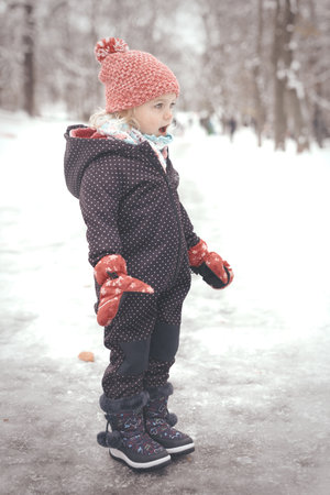 Two years old girl enjoying snow and ice in frozen city parkの写真素材