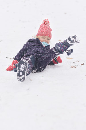 Two years old girl enjoying snow and ice in frozen city parkの写真素材