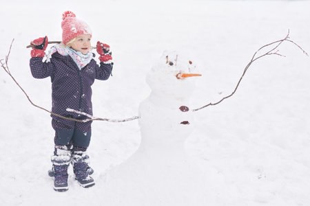 Two years old girl enjoying snow and ice in frozen city park