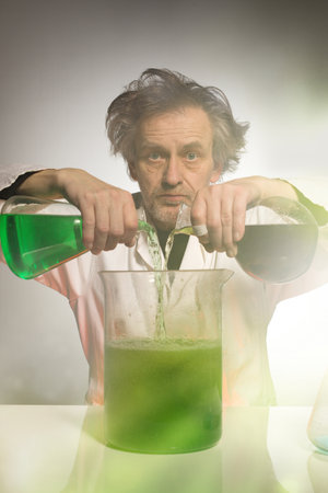 Older crazy chemist preparing a chemical experiment with some liquidsの写真素材