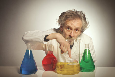 Older crazy chemist preparing a chemical experiment with some liquidsの写真素材