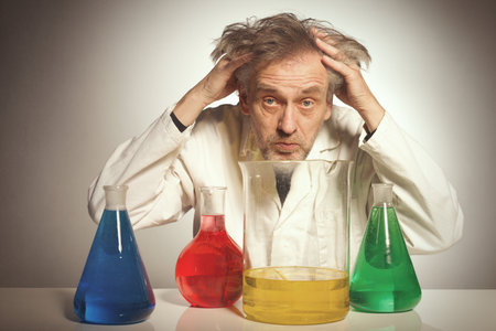 Older crazy chemist preparing a chemical experiment with some liquidsの写真素材