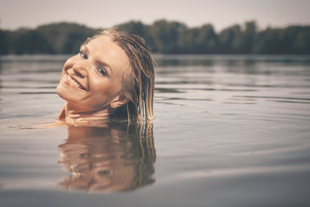 Pretty lady in summer lake posing for portrait in daytimeの写真素材
