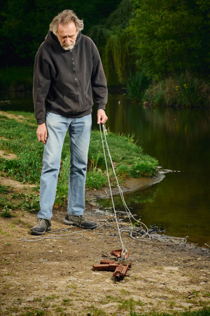 Senior citizen fishing with magnet in city lake