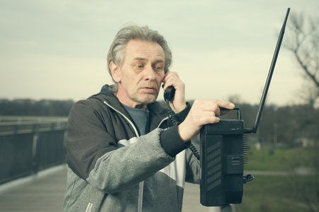 Older man outdoor on bridge using cellphone to callの写真素材