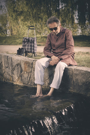 Senior citizen spending time alone in spring park with cartの写真素材