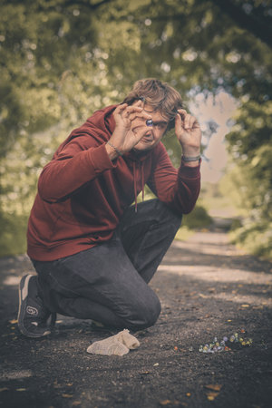 Adult man and his son training classic marbles outdoors on pathway in natureの写真素材