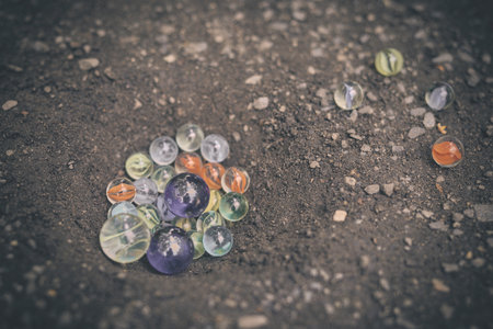 Detail of glass classic marbles outdoor on pathway in hole in ground