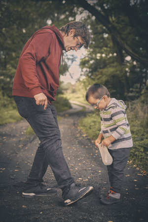 Adult man and his son training classic marbles outdoors on pathway in natureの写真素材