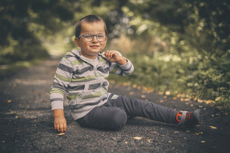 Little boy on dusty path training classic marbles outdoor on pathway in natureの写真素材
