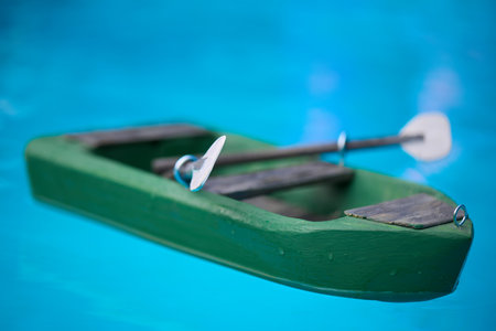 Wooden carved model of small punt with oars floating on level of poolの写真素材