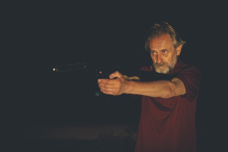 Older man in red shirt with handgunの写真素材