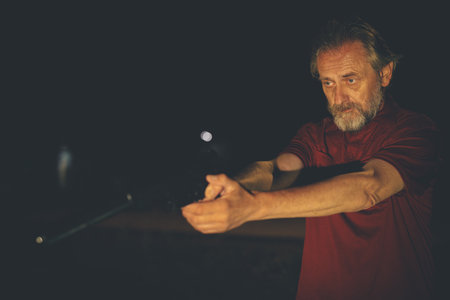 Older man in red shirt with handgunの写真素材