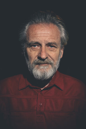 Older man in red shirt waiting for something on night city locationの写真素材