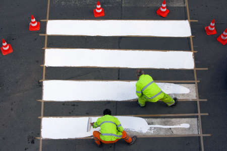 workers painting crosswalk with white colour - view from aboveの写真素材