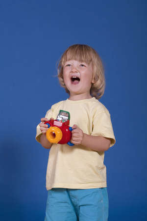 studio shot of a cheerful boy with a colorful plastic cameraの写真素材