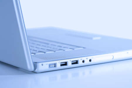 open thin silver laptop computer  on white - side view, blue toneの写真素材