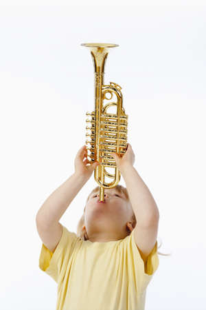 boy with long blond hair playing with toy trumpetの写真素材