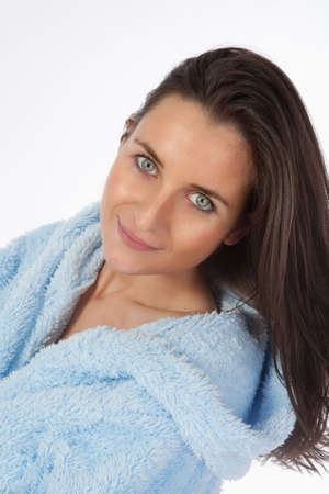 attractive brunette in blue bathrobe with hood isolated on whiteの写真素材