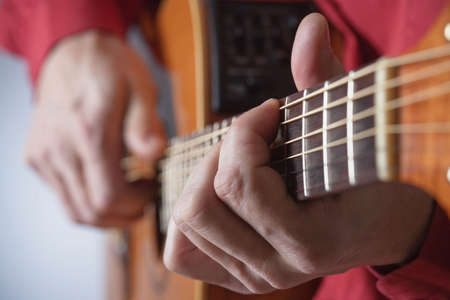 closeup of hands of a musician playing acoustic guitar