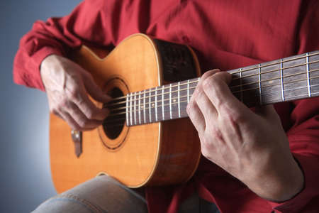 closeup of hands of a musician playing acoustic guitar