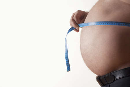 big belly of a fat man and measuring tape isolated on whiteの写真素材