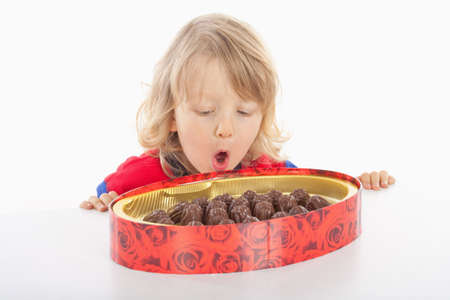 boy with long blond hair and a box of chocolate - isolated on whiteの写真素材
