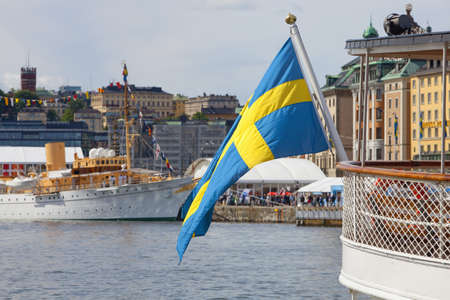 Sweden Stockholm - Swedish flag on one of the many boats anchored at The Old Town - Gamla Stanの写真素材