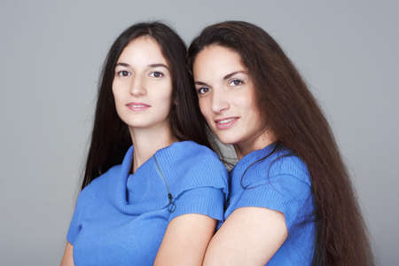 portrait of two sisters with very long brown hair -isolated on gray