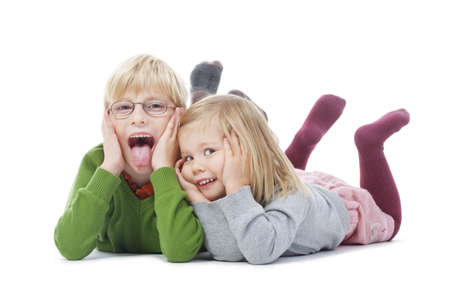 portrait of two young siblings looking at camera, making faces- isolated on whiteの写真素材