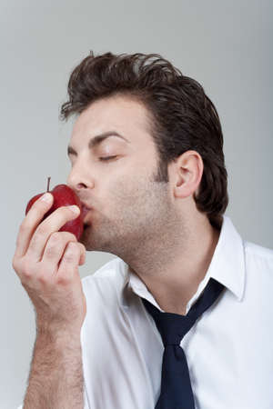 man in white shirt and tie holding red apple - isolated on grayの写真素材