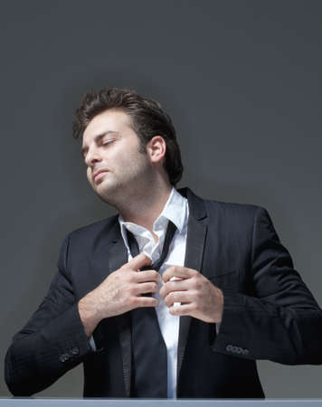 businessman in suit loosening up his tie - isolated on grayの写真素材