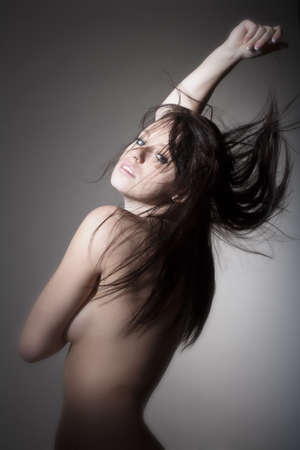 beautiful nude woman with dark hair standing - isolated on grayの写真素材