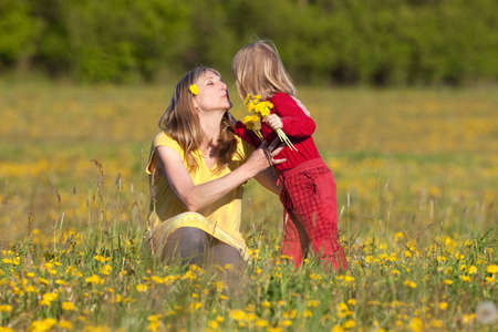 mother and son picking flowers at dandelion field in springの写真素材