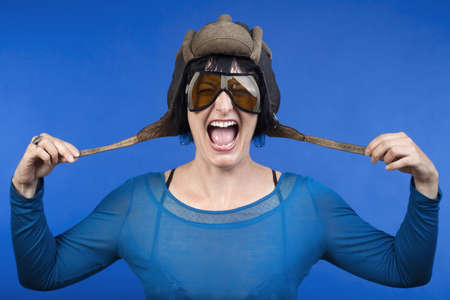 woman with old army tank personal helmet, laughing - isolated on blueの写真素材