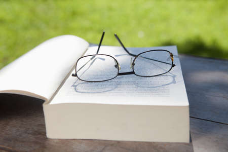 closeup of glasses and an opened book on a table in the gardenの写真素材